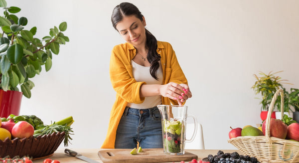 Beautiful brunette woman juicing beverage for healthy detox in her kitchen