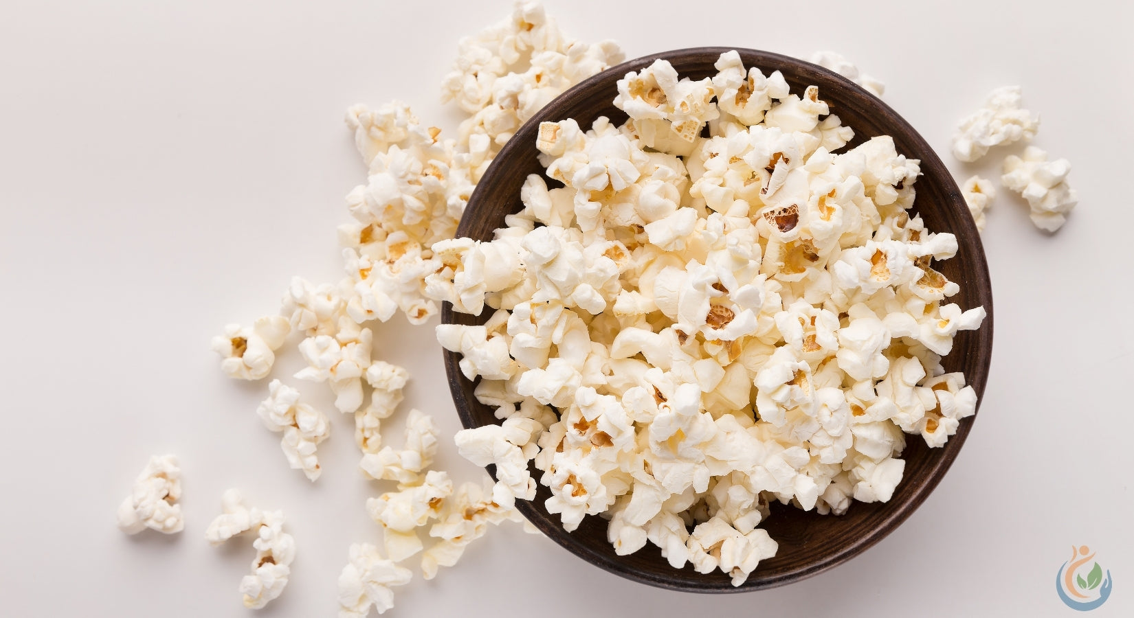 Buttered popcorn spilling out of a brown bowl on a white table