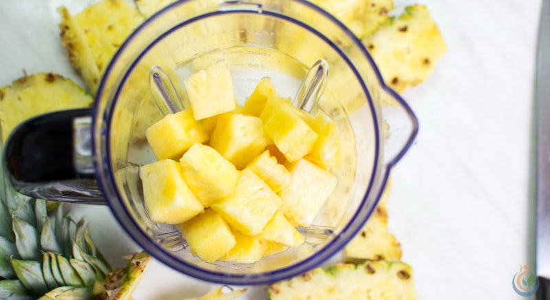 Yellow pineapple chunks inside blender on a white table in the kitchen