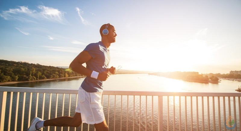 Man running in the morning during sunrise with clear skies wearing blue headphones